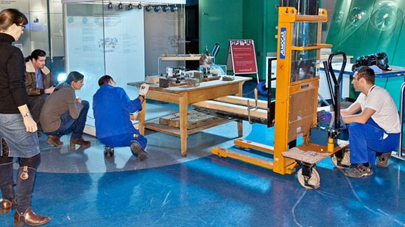 Der Arbeitstisch wird von Museumsexperten behutsam von der Atomphysik in die Museumsgeschichte umgezogen.