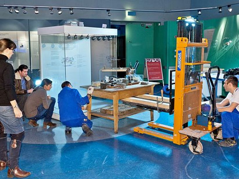 Der Arbeitstisch wird von Museumsexperten behutsam von der Atomphysik in die Museumsgeschichte umgezogen.