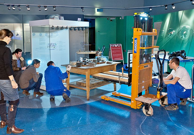 Der Arbeitstisch wird von Museumsexperten behutsam von der Atomphysik in die Museumsgeschichte umgezogen.