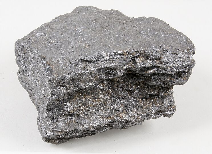 Dunkelgraue, metallisch glänzende Probe von Graphit mit schuppiger Oberfläche.