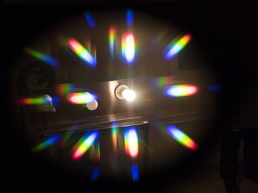 Angeschaltene Glühbirne wirft Lichtstrahlen, an denen man die Fraunhofer-Linien erkennen kann.