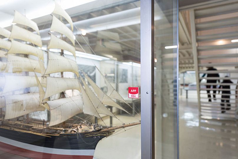 Museumsapp-Plakette an einer Vitrine der Ausstellung Schifffahrt.