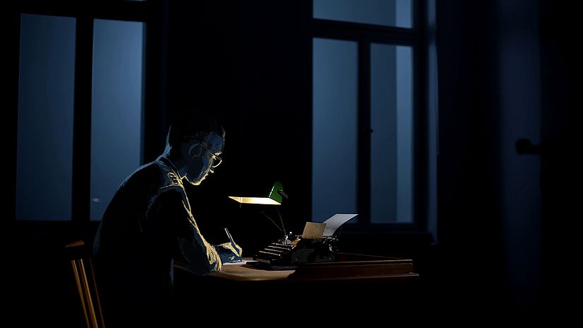 Diese Zeichnung zeigt Fritz Menzer wie er im Dunkeln an seinem Schreibtisch sitzt und arbeitet.