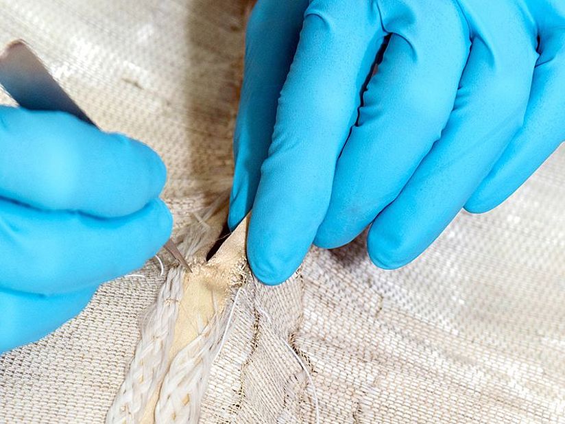 Hände in Handschuhen am Glasfaserkleid.