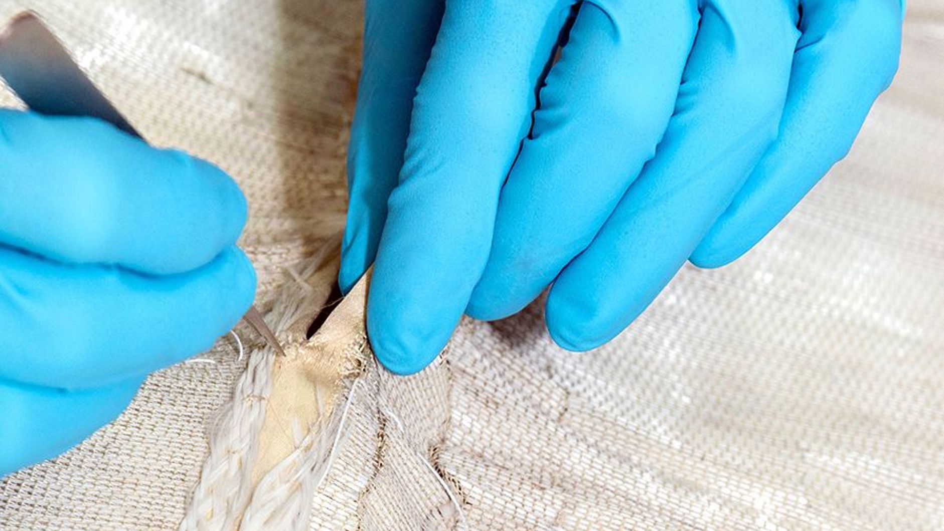 Hände in Handschuhen am Glasfaserkleid.
