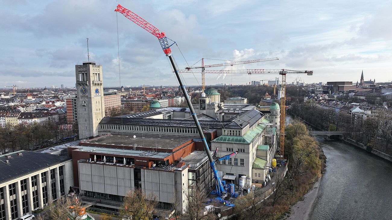 Blick von oben auf das Deutsche Museum an der Isar mit einem großen Autokran, der sich über die Gebäude erhebt