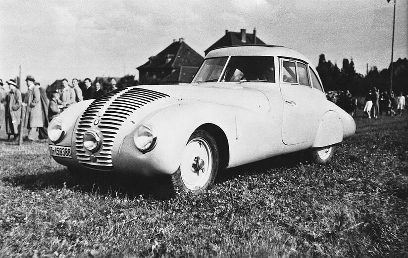 Schwarz-weiß Fotografie zeigt den BMW Wendler von der Seite. Das Auto steht auf einer Wiese.