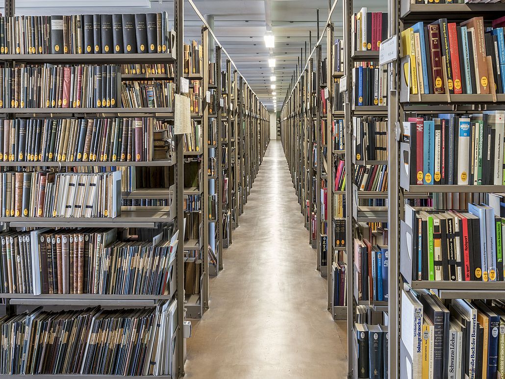 Ein Gang zwischen den gefüllten Bücherregalen des Bibliotheksmagazins.