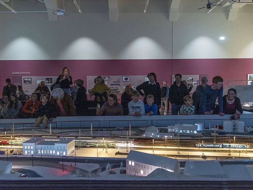 Besucherinnen und Besucher schauen gespannt die Vorführung der Modellbahnanlage an.