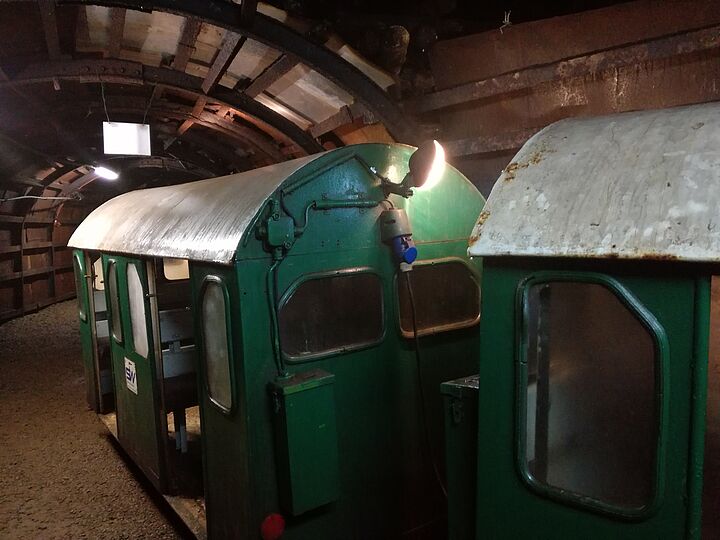 Das Innere eines Stohlens. Zwei kleine Wagen (grün lackiert mit grauen Dächern) sind im Vordergrund.