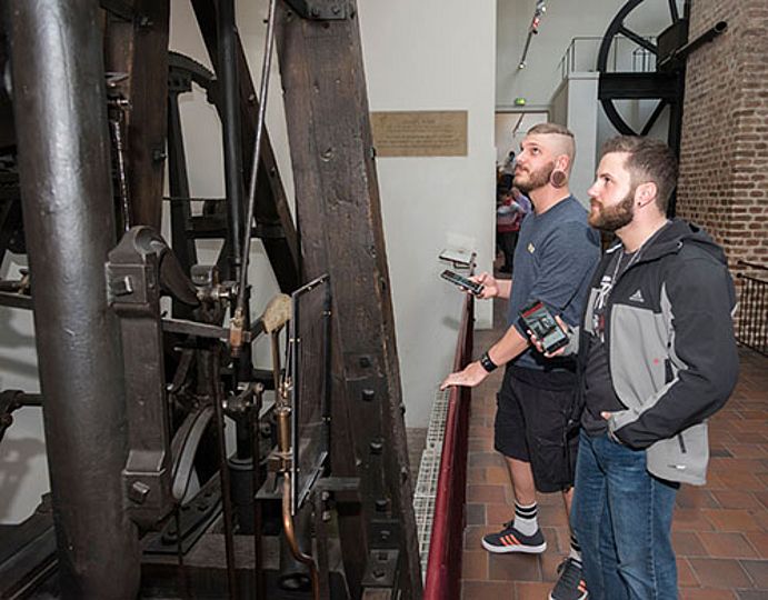 Zwei Besucher in der Ausstellung Kraftmaschinen während der Nutzung der Museumsapp.