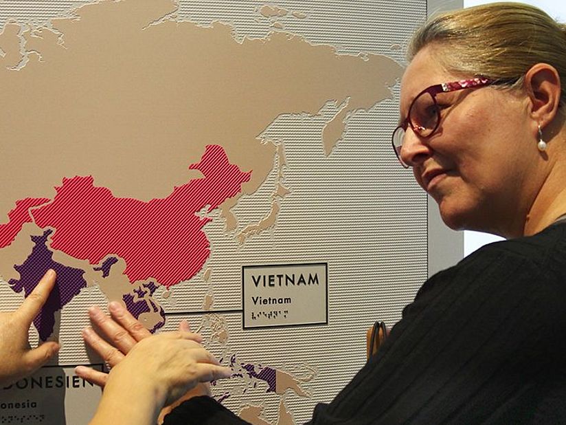 Frau ertastet Weltkarte mit den Orten des Kaffeeanbaus.