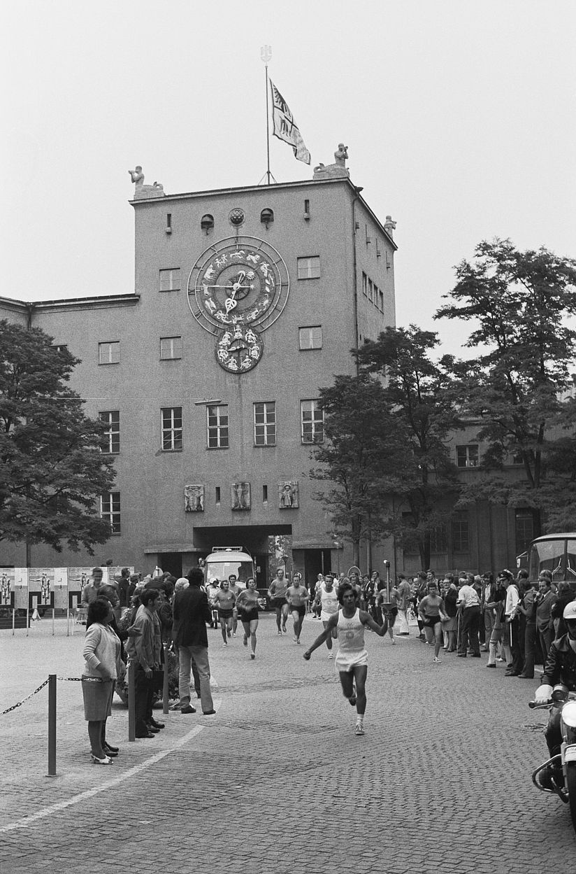 Das Foto, das einer der Fotografen des Deutschen Museums damals gemacht hat, zeigt, wie der Läufer von der Zenneckbrücke, aus Richtung Osten kommend, den Museumshof durchquert, angefeuert von vielen Umstehenden, gefolgt von weiteren Läuferinnen und Läufern.