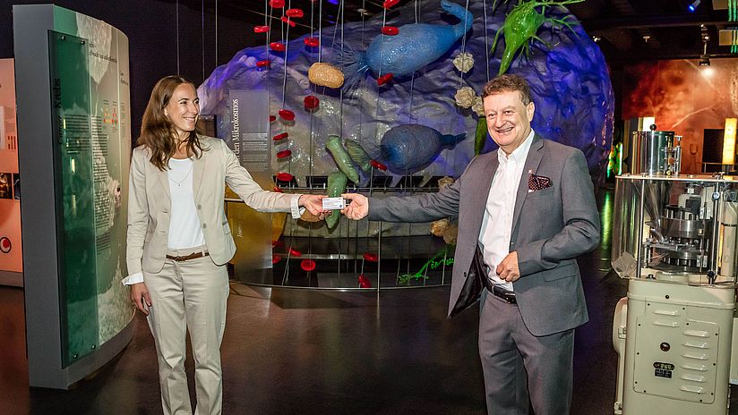 Chantal Friebertshäuser, übergibt Generaldirektor Wolfgang M. Heckl den neuen Impfstoff „Ervebo“. 