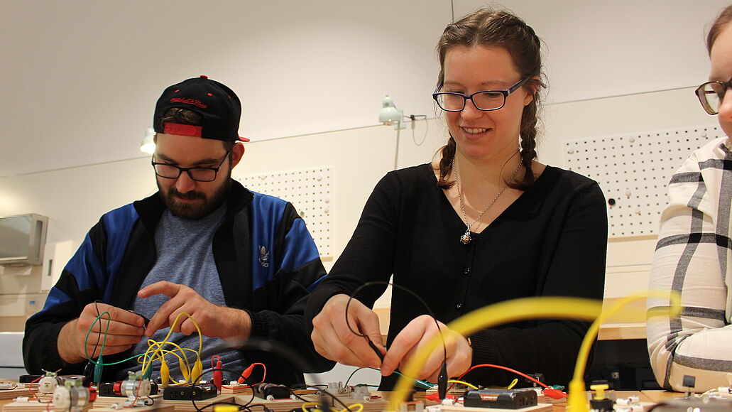 Elektronik-Werkstatt Zwei junge Erwachsene bauen mit unterschiedlichen Elementen Stromkreise zusammen.
