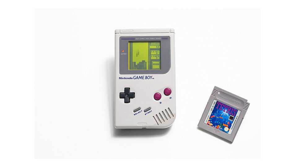 Dieser Gameboy-Klassiker ist das erste Exemplar in einer Reihe von Handheld-Konsolen. Er kam 1989 in Japan und den USA und ein Jahr später in Europa auf den Markt. Schnell wurde er zum Kultobjekt und bald zur erfolgreichsten Spielkonsole aller Zeiten. Die Anfänge der Konsolenspiele waren einfach: Begonnen hatte alles mit dem Spiel Tetris, das trotz farbloser Grafik – lediglich vier Grauabstufungen konnten dargestellt werden – zum Kult wurde und den Erfolg der handlichen Gameboy-Konsole ermöglichte. Auch seine für damalige Verhältnisse geringe Größe und die lange Batterielaufzeit verhalfen dem Gameboy zum Durchbruch.