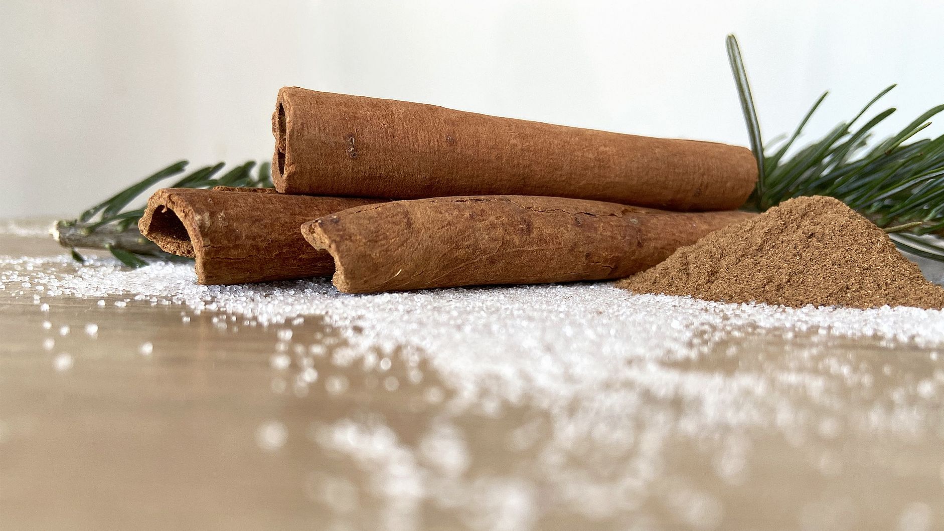 Zimtstangen mit gemahlenem Zimt, Zucker und Tannenzweig