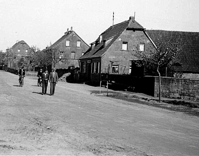 Schwarz-weiss Photografie von 1954, Dorfstrasse mit Passanten.
