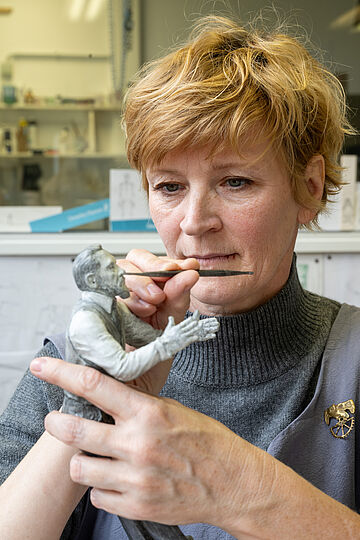 Elisabeth Straßer hält eine Figur in der Hand und bearbeitet sie.