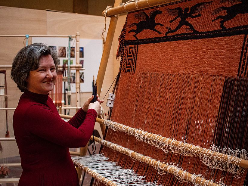 Ellen Harlizius-Klück vor antikem Webstuhl.