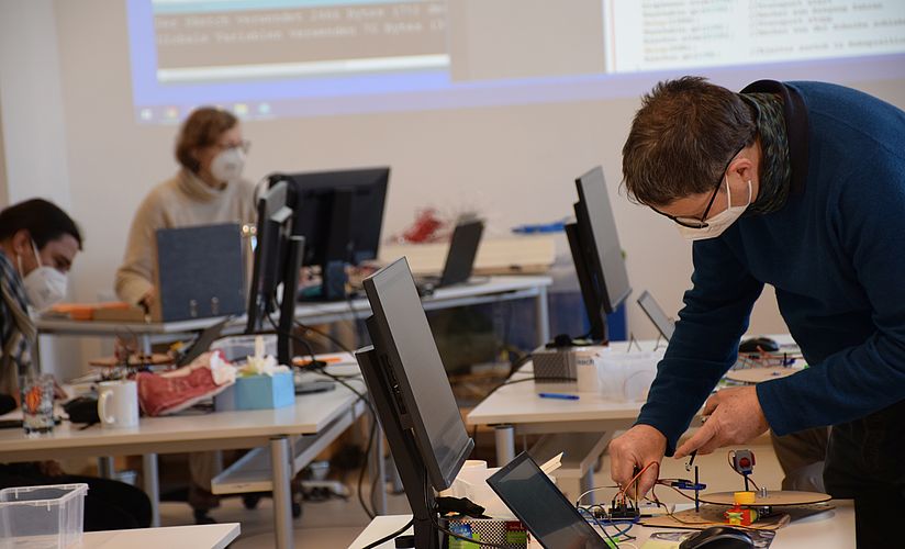 Lehrerinnen und Lehrer erproben die Mini-Produktionsanlage.