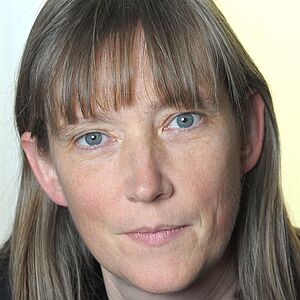 Eine Person mit schulterlangem, graubraunem Haar und Mittelscheitel, sichtbare Ohren und Hals, Vorderansicht; Gesicht aus Datenschutzgründen unkenntlich gemacht.