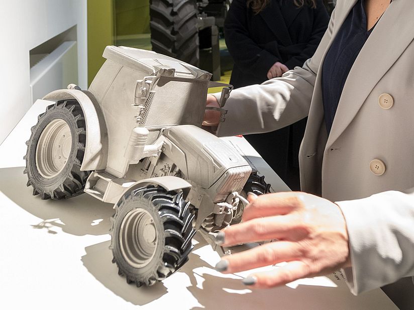 Verena Bentele tastet ein Tastmodell eines Traktors ab.