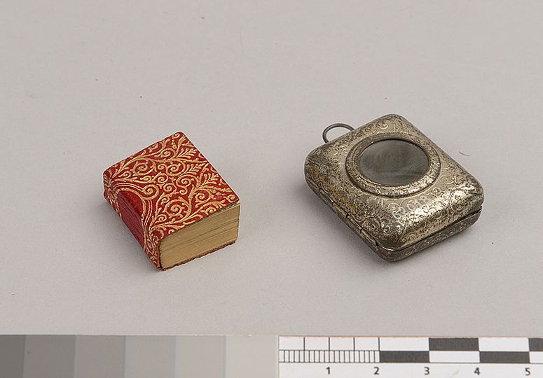 Miniatur Koran neben Silberkapsel.
