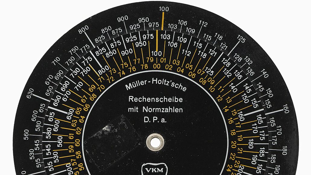 Schwarze runde Scheibe mit mehreren kreisförmig angeordneten Skalen (weiß und gelb gedruckt)