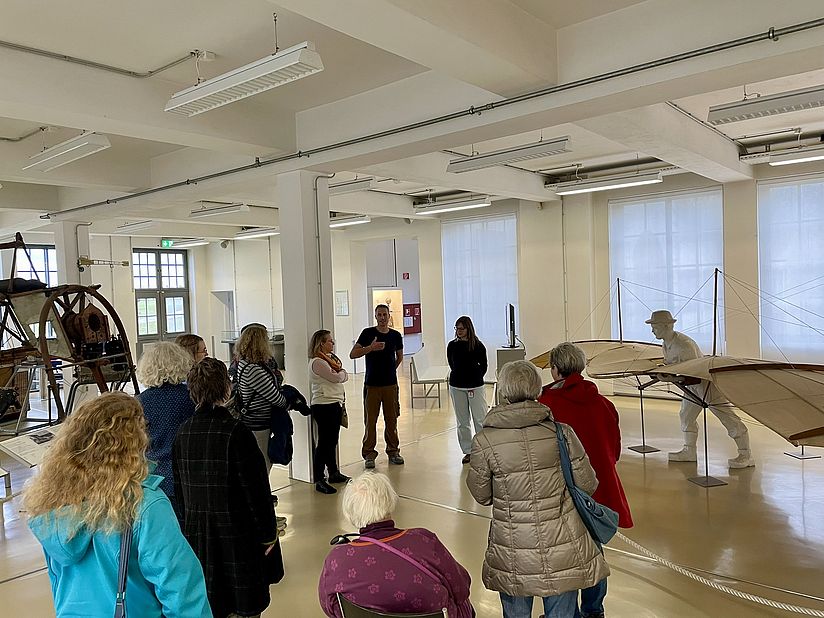 Alle Teilnehmerinnen während der Einführung von Charlotte Holzer und Patrick Goldbach vor einem Nachbau des Normal-Segelapparats von Otto Lilienthal.