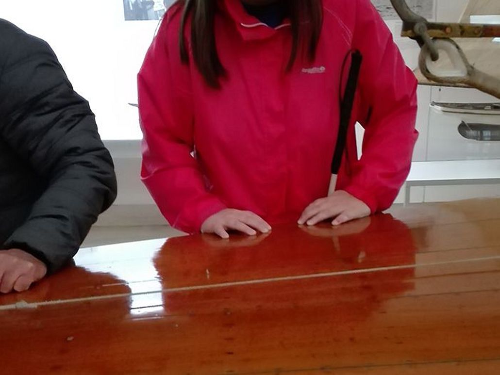 Hände gleiten über Holz eines Schiffs.