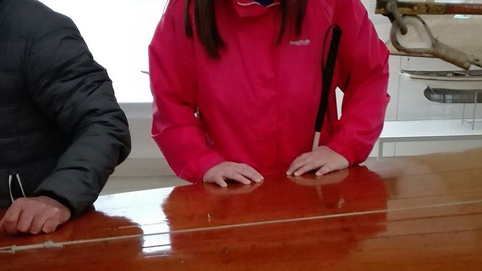 Hände gleiten über Holz eines Schiffs.