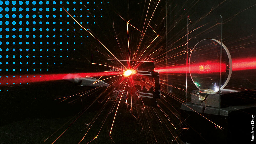 Laser trifft auf Rasierklinge und erzeugt Lichtfunken.