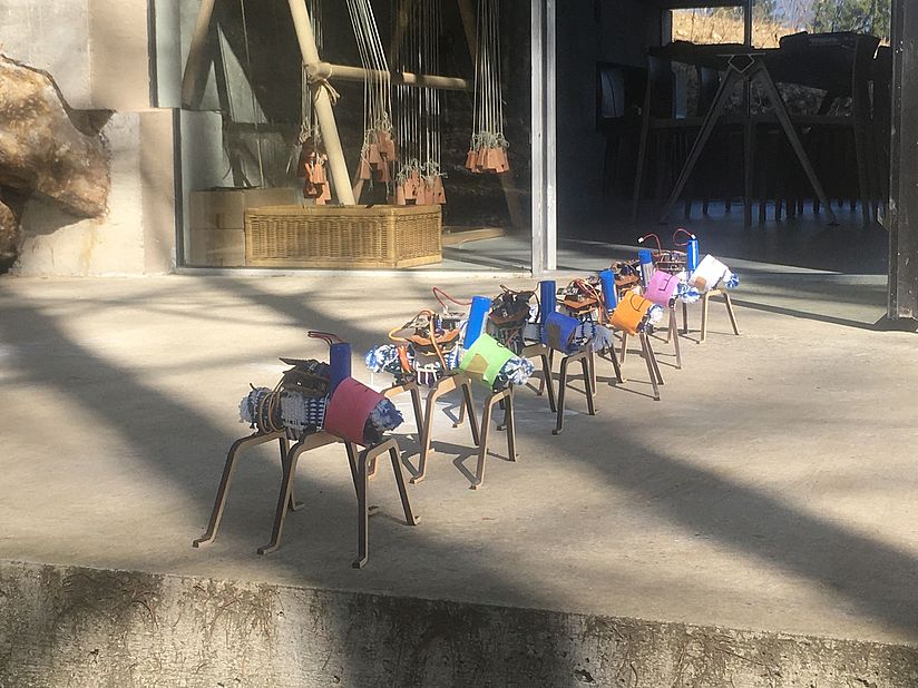 Roboter auf der Terrasse mit dem Gewichtswebstuhl im Hintergrund. 