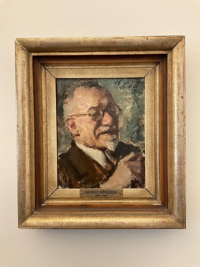 Fotografie eines Gemäldes von Arnold Berliner. Bild in expressionistischem Stil zeigt Porträt von Berliner mit Zigarre. Rahmen ist stark und goldfarben.