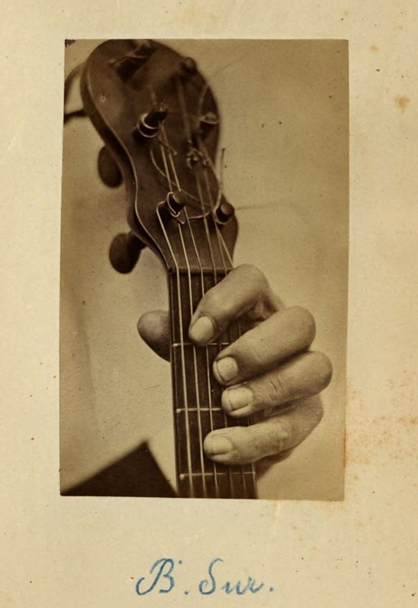 Alte Fotografie zeigt Hand am Griff einer Gitarre.